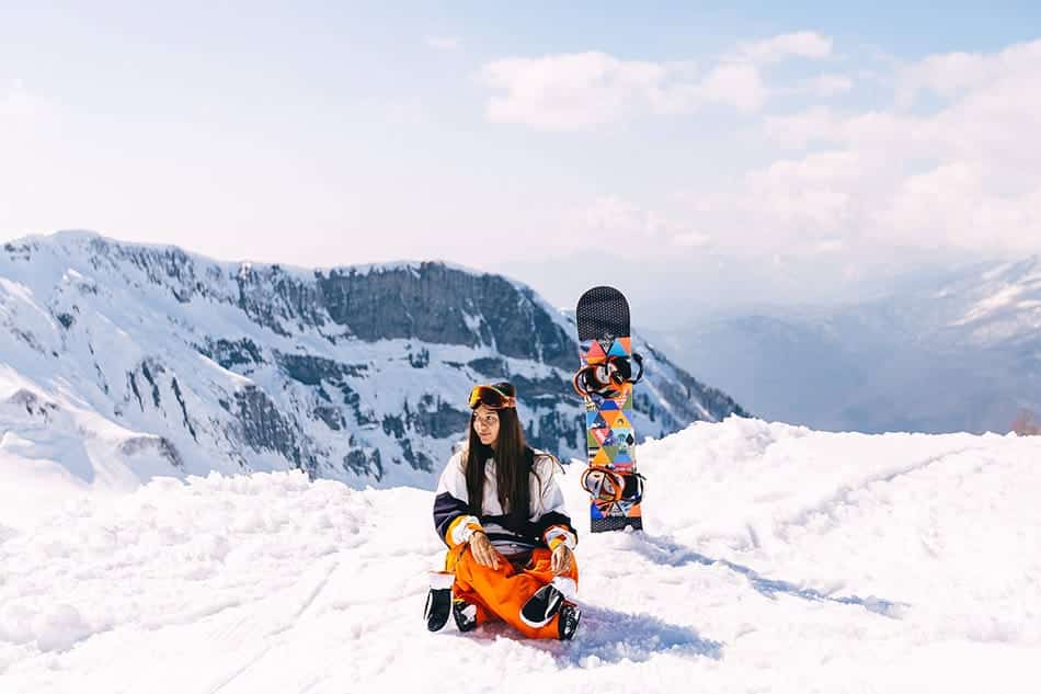 ragazza sulla neve con tavola da snowboard